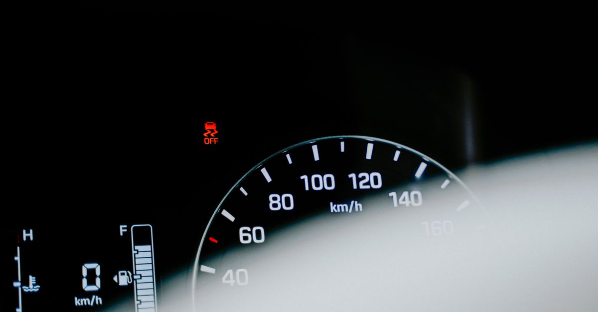 Detailed close-up of a car speedometer displaying a digital reading and warning light.